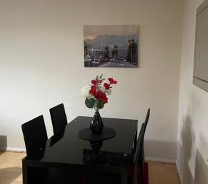 a dining room table with a vase of flowers on it at NNK Air BnB in Ponders End
