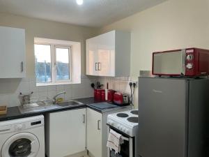 a small kitchen with a refrigerator and a microwave at NNK Air BnB in Ponders End