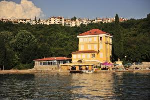 a large yellow building on the shore of a body of water at Bed&Breakfast Villa Eva in Omišalj
