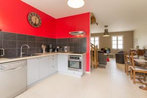 - une cuisine avec des murs rouges et un sol blanc dans l'établissement Maison Baduel, à Auxey-Duresses
