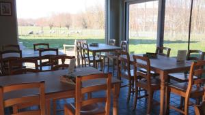 a room with tables and chairs and a large window at Hoevehotel Ronse in Ronse