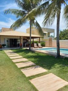 uma casa com palmeiras e uma piscina em Uma Casa para o Descanso! em Camaçari