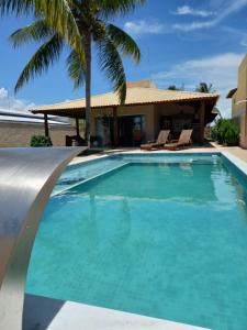 una piscina con agua azul y palmeras en Uma Casa para o Descanso!, en Camaçari