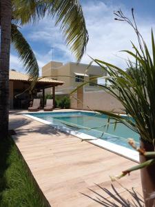 a swimming pool next to a house with a palm tree at Uma Casa para o Descanso! in Camaçari
