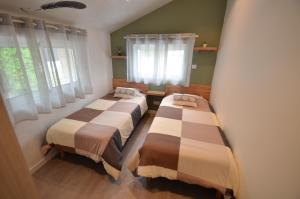 Dos camas en una habitación con dos ventanas. en Maison Bon Air Capbreton, en Capbreton