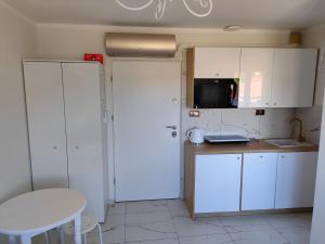 eine Küche mit weißen Schränken, einem Tisch und einer Mikrowelle in der Unterkunft Apartament Centrum in Ustroń