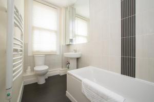 a white bathroom with a tub and a toilet at Unique and Cozy 1 Bed Flat in Dalston in London