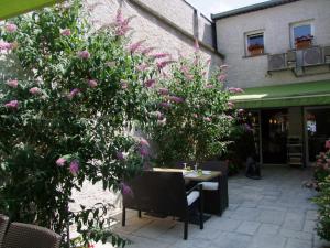 a table and chairs in a garden with pink flowers at LOGIS Le CANTAREL 