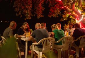 a group of people sitting at a table in a restaurant at Sunset Beach View in Dhangethi