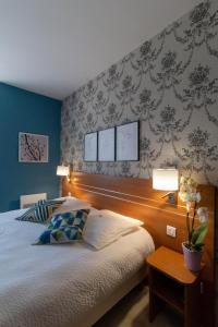 a bedroom with a bed and a table with two lamps at LOGIS Le CANTAREL 