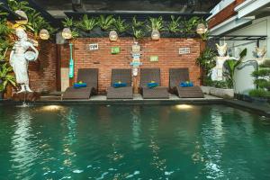 uma piscina com cadeiras em frente a um edifício em Ubudku Villas em Ubud
