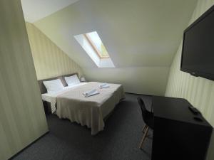 a room with a bed, table and a television at Bohema, Tubinas Hotels in Klaipėda