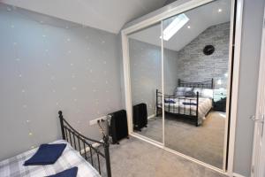a bedroom with a mirror and a bedroom with a bed at Stylish ground floor conversion near Bath and Priston with outstanding views in Priston
