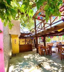 un restaurante con mesas de madera y sillas bajo un árbol en La Luz Hostal Cancun en Cancún