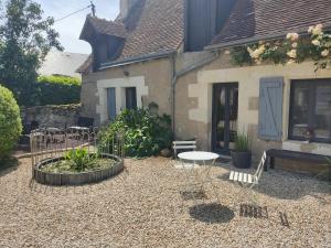 un patio con tavolo e sedie di fronte a una casa di Au Jardin de la Marquetterie a Cigogné