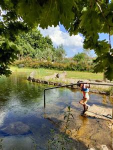 a person is standing in the water with a fishing pole at Casa Das Palmeiras-Pedagogic Farm in Mangualde