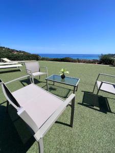 a group of chairs and a table on a lawn at La Costa Est Villa con Vista Mare in Ogliastra Sardegna in Tertenìa