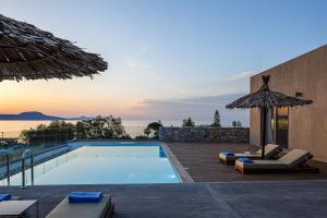a swimming pool with lounge chairs and an umbrella at Aristotelis Residence in Petres