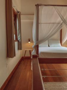 a small bedroom with a bed with a canopy at Villa Estrela Bungalow in Itacaré