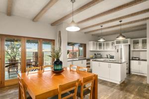 Una cocina con una mesa de madera y una cocina con gabinetes blancos. en Elements Private Golf Reserve House 296, en Bela-Bela