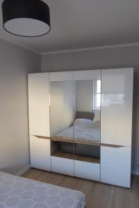 a bedroom with a white cabinet with a bed at Dziwnówek Słoneczne Tarasy Gray in Dziwnówek
