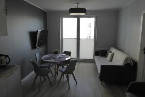 a living room with a table and chairs and a couch at Dziwnówek Słoneczne Tarasy Gray in Dziwnówek