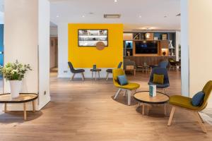 a waiting room with chairs and a yellow wall at Holiday Inn Lyon Vaise by IHG in Tassin-la-Demi-Lune