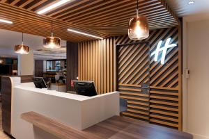 an office lobby with a reception desk and chairs at Holiday Inn Lyon Vaise by IHG in Tassin-la-Demi-Lune
