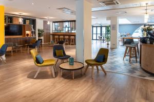 a waiting area with chairs and tables in a lobby at Holiday Inn Lyon Vaise, an IHG Hotel in Tassin-la-Demi-Lune