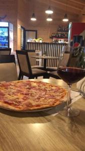 a pizza sitting on a table next to a glass of wine at Hotel Real in Ishull-Lezhë