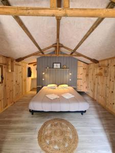 ein Schlafzimmer mit einem großen Bett in einem Zimmer mit Holzwänden in der Unterkunft Camping Aux Couleurs du ferret in Lège-Cap-Ferret