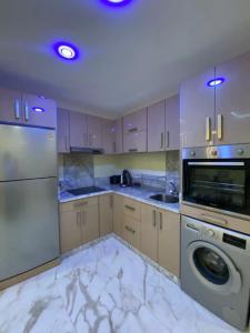 cocina con suelo de mármol blanco, lavadora y secadora en Magnifique appartement avec terrasse prive vue mer en Esauira