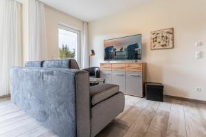 ein Wohnzimmer mit einem Sofa und einem TV in der Unterkunft Strandresidenz Dünenperle, App 6 in Kühlungsborn