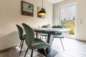 ein Esszimmer mit einem Tisch und grünen Stühlen in der Unterkunft Strandresidenz Dünenperle, App 6 in Kühlungsborn