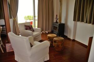 a living room with two white chairs and a stove at Maison de la mer in Témeni