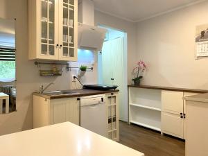 a kitchen with white cabinets and a sink at Forest - 23 Marca Sopot by Grand Apartments in Sopot