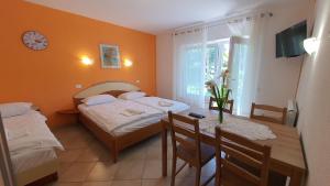 a bedroom with two beds and a table and a clock at Peaceful Green Apartments AE in Portorož