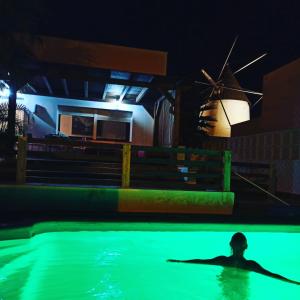 un homme nageant dans une piscine la nuit avec un moulin à vent dans l'établissement Casita del Molino, à Las Negras