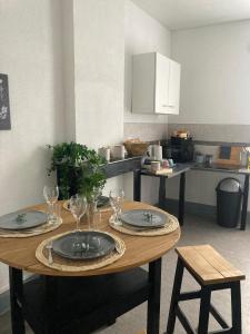 a kitchen with a table with plates and wine glasses at Spacieux Proche Zone Industrielle Tout confort in Feignies