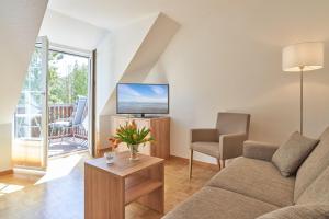 uma sala de estar com um sofá e uma televisão em Hotel Weisser Hof em Malente