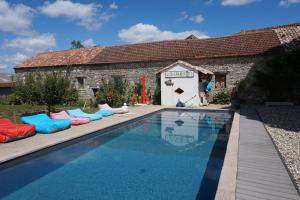 a swimming pool with lounge chairs next to a building at Au Bonheur d'Alphonse in Lusignan-Petit