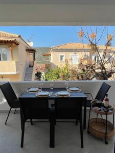 a black table with wine glasses on a balcony at Lovely 2-bedroom apartment in the heart of Ermioni in Ermioni