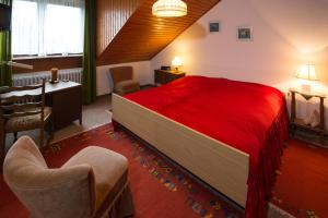 een slaapkamer met een rood bed, een bureau en een stoel bij Ferienwohnungen Casa Ri(e)sig in Leiwen