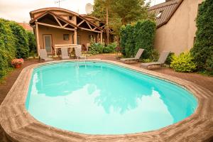 a swimming pool with blue water in front of a house at Palangos Saulegraza in Palanga