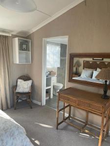 een slaapkamer met een bed, een tafel en een spiegel bij Lakeside Cottage on Spring Grove in Nottingham Road
