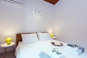 a bedroom with a white bed with two tables at Corfu Anemoessa Apt in Glyfada