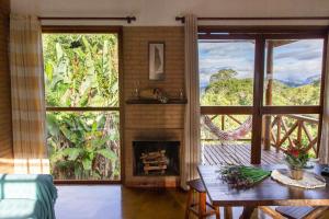 a living room with a fireplace and a table with a view at Pousada Vitoria in Gonçalves