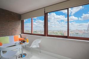 a room with windows and a table and chairs at Hotel Chamartin The One in Madrid