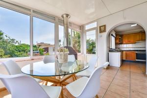 une salle à manger avec une table en verre et des chaises blanches dans l'établissement Villas Guzman - Mouna, à Calp