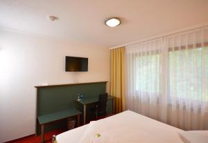 a bedroom with a bed and a desk and a television at Hotel Kehrenkamp in Hagen